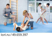 Diligent preteen student twisting his opponent's arm on the floor. Стоковое фото, фотограф Яков Филимонов / Фотобанк Лори