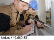 grading the apprentice's window installation. Стоковое фото, агентство Ingram Publishing / Фотобанк Лори