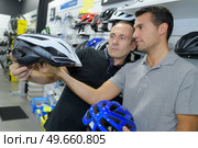 man chooses helmet for cycling before buying in sports shop. Стоковое фото, агентство Ingram Publishing / Фотобанк Лори