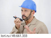 builder gesticulating while communicating on walkie talkie. Стоковое фото, агентство Ingram Publishing / Фотобанк Лори