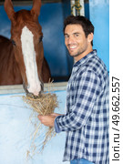 farrier petting and fed horse with hay. Стоковое фото, агентство Ingram Publishing / Фотобанк Лори
