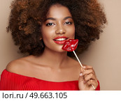 Beautiful portrait of an African girl with a lips shaped lollipop. Valentine’s Day. Symbol of love. Стоковое фото, агентство Ingram Publishing / Фотобанк Лори