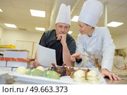 portrait of hospitable chef with young smiling female helper. Стоковое фото, агентство Ingram Publishing / Фотобанк Лори