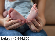 Gentle Care a Mother's Hands Lovingly Cradle Her Infant's Tiny Feet. Стоковое фото, фотограф Aleksandr Golubev / Фотобанк Лори