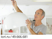 handsome senior builder installs a lamp. Стоковое фото, агентство Ingram Publishing / Фотобанк Лори