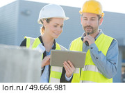 colleagues outdoors wearing reflective vests looking at tablet. Стоковое фото, агентство Ingram Publishing / Фотобанк Лори
