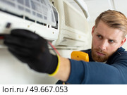 young man repairing air conditioner indoors. Стоковое фото, агентство Ingram Publishing / Фотобанк Лори