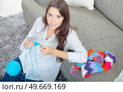 Girl sat on floor knitting. Стоковое фото, агентство Ingram Publishing / Фотобанк Лори