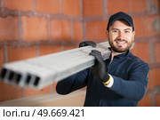 construction worker carrying reinforcement rods at building site. Стоковое фото, агентство Ingram Publishing / Фотобанк Лори