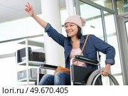 young woman in wheelchair gestyring hello and smiling. Стоковое фото, агентство Ingram Publishing / Фотобанк Лори