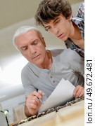 carpenter is writing something with apprentice. Стоковое фото, агентство Ingram Publishing / Фотобанк Лори
