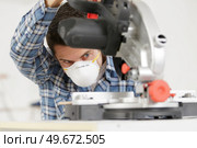 repairman standing with electric saw in mask. Стоковое фото, агентство Ingram Publishing / Фотобанк Лори