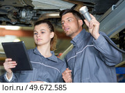man and woman mechanic examine the underside of a car. Стоковое фото, агентство Ingram Publishing / Фотобанк Лори