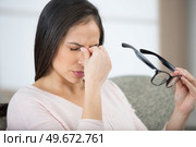 woman holding glasses to rub the bridge of her nose. Стоковое фото, агентство Ingram Publishing / Фотобанк Лори