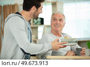 mature son congratulating elderly father. Стоковое фото, агентство Ingram Publishing / Фотобанк Лори