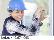 woman builder unscrews window handle. Стоковое фото, агентство Ingram Publishing / Фотобанк Лори
