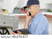 senior man phoning support line for guidance installing appliance. Стоковое фото, агентство Ingram Publishing / Фотобанк Лори