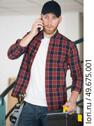 tradesman entering premises talking on his smartphone. Стоковое фото, агентство Ingram Publishing / Фотобанк Лори