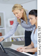 young woman learning play piano with teacher. Стоковое фото, агентство Ingram Publishing / Фотобанк Лори