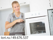 female electrician fixing oven unit. Стоковое фото, агентство Ingram Publishing / Фотобанк Лори