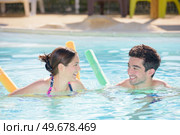 Man and woman in swimming pool with floats. Стоковое фото, агентство Ingram Publishing / Фотобанк Лори