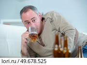 mature drunk man drinks a beer on the sofa. Стоковое фото, агентство Ingram Publishing / Фотобанк Лори