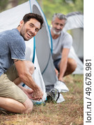 two mature men erecting a tent. Стоковое фото, агентство Ingram Publishing / Фотобанк Лори