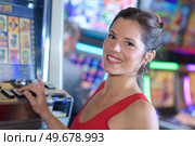 beautiful woman in red dress playing slot machine. Стоковое фото, агентство Ingram Publishing / Фотобанк Лори