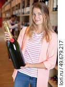 woman holding a magnum of champagne in an alcohol store. Стоковое фото, агентство Ingram Publishing / Фотобанк Лори