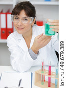 female lab worker holding a flask with green chemical liquids. Стоковое фото, агентство Ingram Publishing / Фотобанк Лори