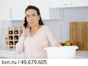 woman calling plumber to fix water leaking from ceiling. Стоковое фото, агентство Ingram Publishing / Фотобанк Лори