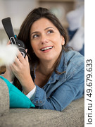 happy young woman in headphones lying on couch a home. Стоковое фото, агентство Ingram Publishing / Фотобанк Лори