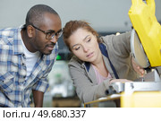 experienced worker helping diligent woman to use a circular saw. Стоковое фото, агентство Ingram Publishing / Фотобанк Лори