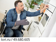 portrait of a man in a wheelchair by the oven. Стоковое фото, агентство Ingram Publishing / Фотобанк Лори