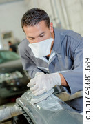 a mechanic sanding car bumper. Стоковое фото, агентство Ingram Publishing / Фотобанк Лори