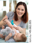 mother putting diaper on her happy baby in nursery. Стоковое фото, агентство Ingram Publishing / Фотобанк Лори