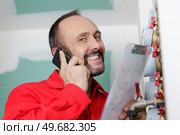 technician on the phone inspecting heating system in boiler room. Стоковое фото, агентство Ingram Publishing / Фотобанк Лори
