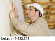 male builder removing old wallpaper for redecorating. Стоковое фото, агентство Ingram Publishing / Фотобанк Лори