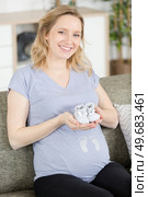 pregnant woman is holding small shoes for the unborn baby. Стоковое фото, агентство Ingram Publishing / Фотобанк Лори