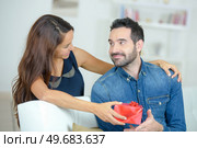 pretty brunette surprising boyfriend with a gift at home. Стоковое фото, агентство Ingram Publishing / Фотобанк Лори