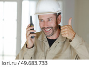 male builder making thumbs up gesture while talking on walkie-talkie. Стоковое фото, агентство Ingram Publishing / Фотобанк Лори