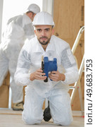 Portrait of man kneeling on floor holding sander. Стоковое фото, агентство Ingram Publishing / Фотобанк Лори