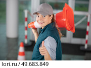 happy female builder holding traffic cone. Стоковое фото, агентство Ingram Publishing / Фотобанк Лори