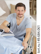 happy disabled man on wheelchair ironing clothing. Стоковое фото, агентство Ingram Publishing / Фотобанк Лори