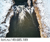 Waterfall on winter creek. Snow on frozen riverbanks. Top Aerial View Of River Cascade. Stream water flowing between rocks. Europe. Стоковое фото, агентство Ingram Publishing / Фотобанк Лори