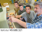 Student switching on machine with instructor's assistance. Стоковое фото, агентство Ingram Publishing / Фотобанк Лори