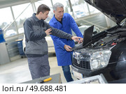 auto mechanic teacher and trainee performing tests at mechanic school. Стоковое фото, агентство Ingram Publishing / Фотобанк Лори