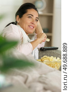 a woman is eating chips while watching tv. Стоковое фото, агентство Ingram Publishing / Фотобанк Лори