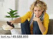 woman frightened by programme is changing channel. Стоковое фото, агентство Ingram Publishing / Фотобанк Лори