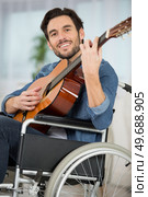 portrait of wheelchair bound man playing acoustic guitar. Стоковое фото, агентство Ingram Publishing / Фотобанк Лори
